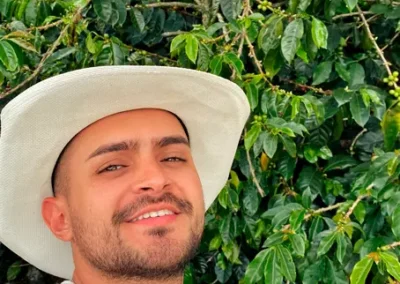 Caficultor sonriendo junto a plantas de café en finca tradicional cerca de Medellín