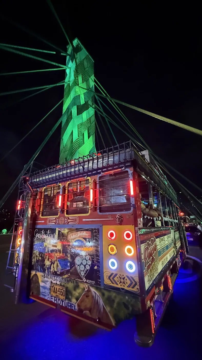 Chiva Rumbera del Tour Medellín pasando por el Puente de la 4 Sur con luces de colores y ambiente festivo