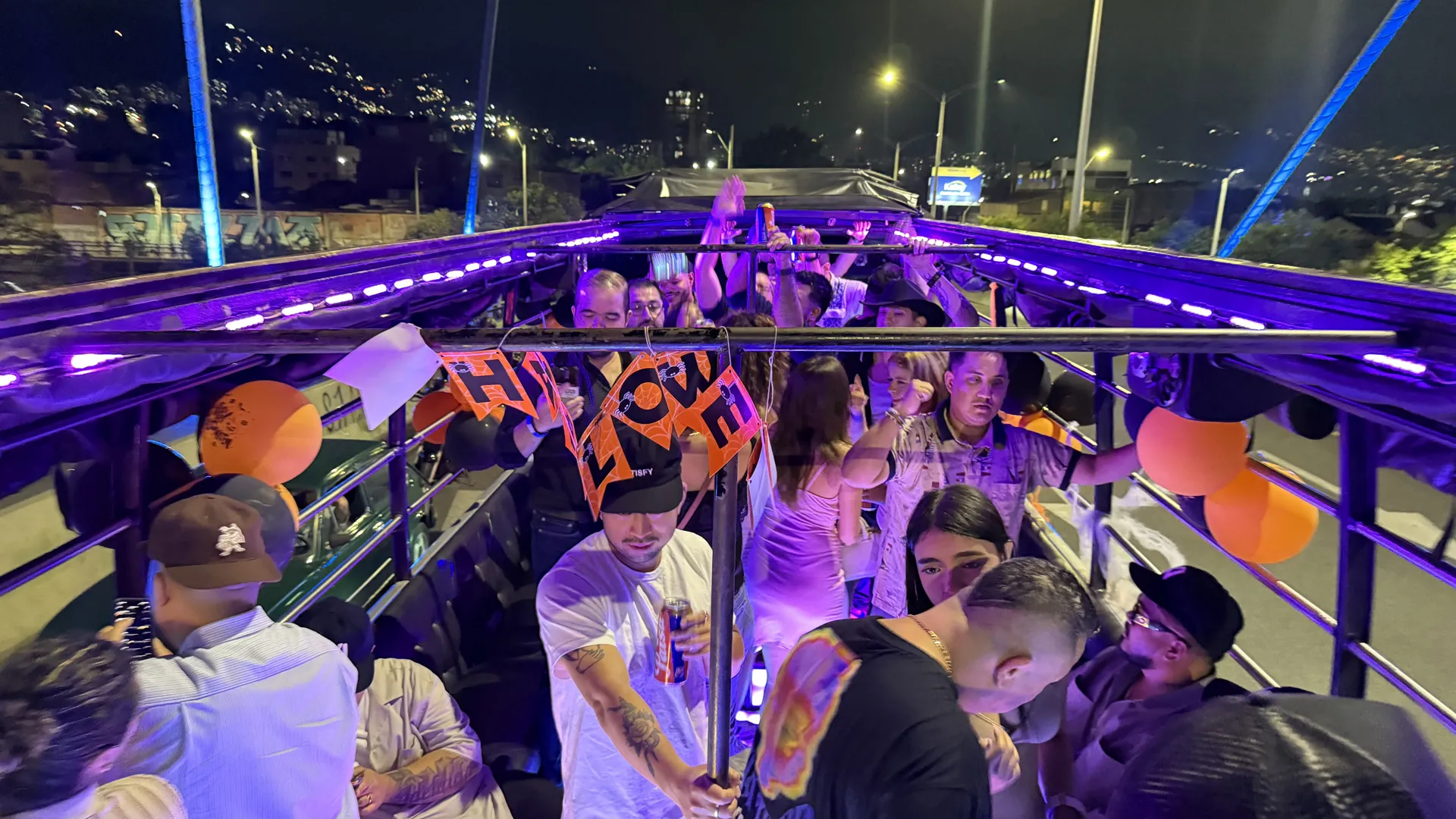 Grupo de personas disfrutando del Tour Party Bus Medellín con cerveza ilimitada, luces y música en vivo durante la noche